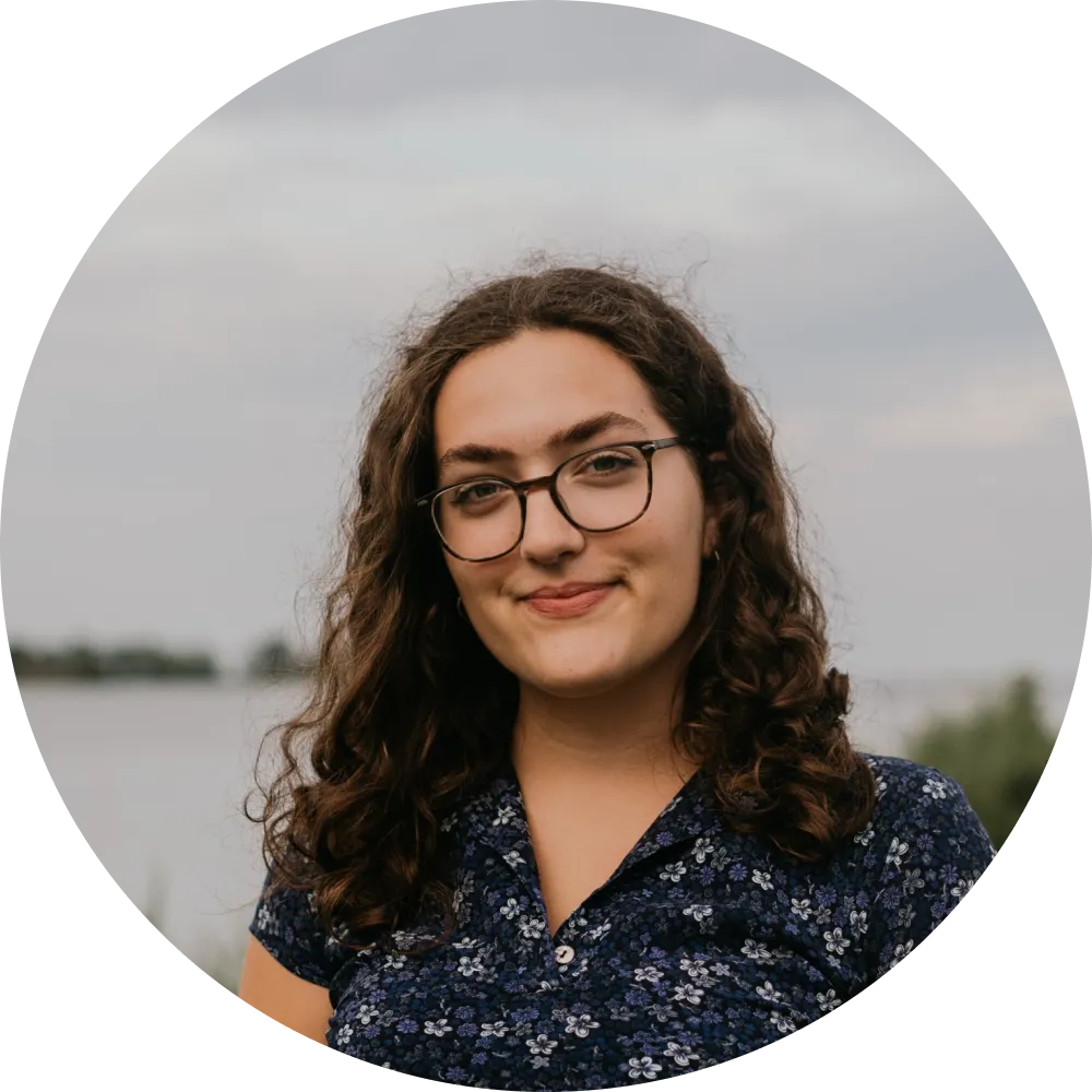 An image of a girl wearing glasses smiling at the camera.