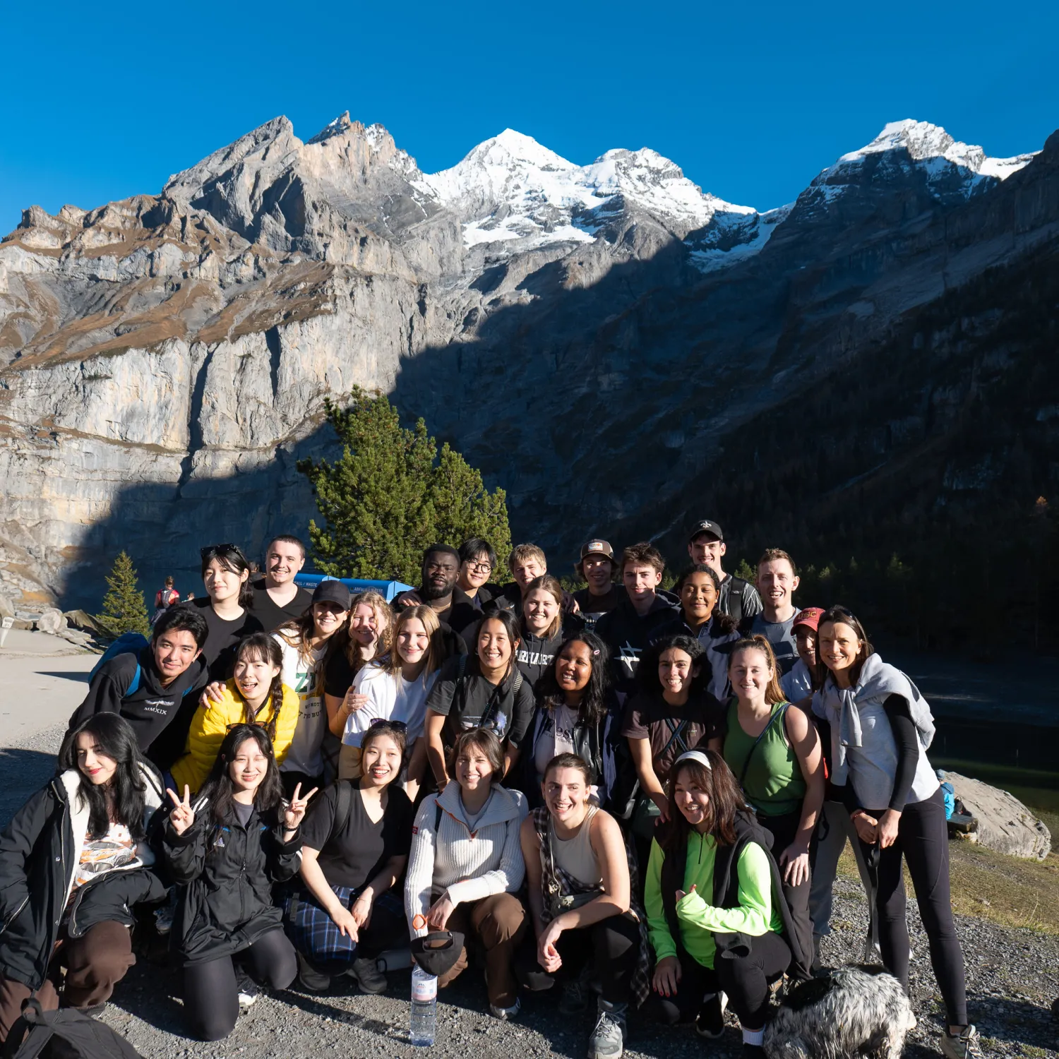 A group of students smiling and posing for a photo in front of snowy mountains.