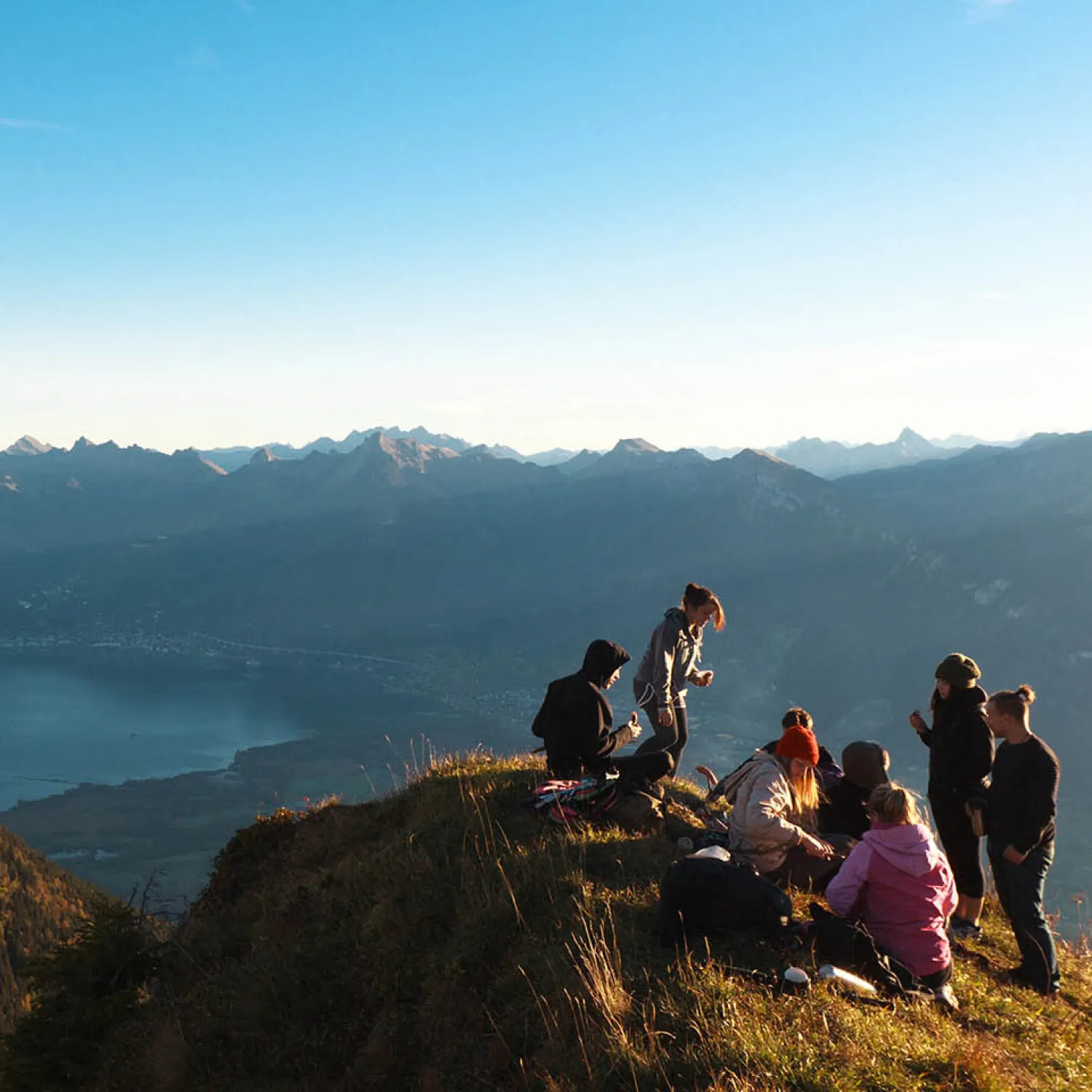 Students gathered at the top of a mountain overlooking a view of a lake.