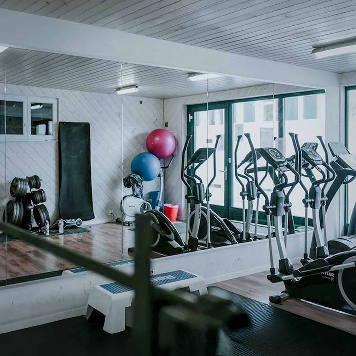 A gym studio with mirrors and gym equipment.