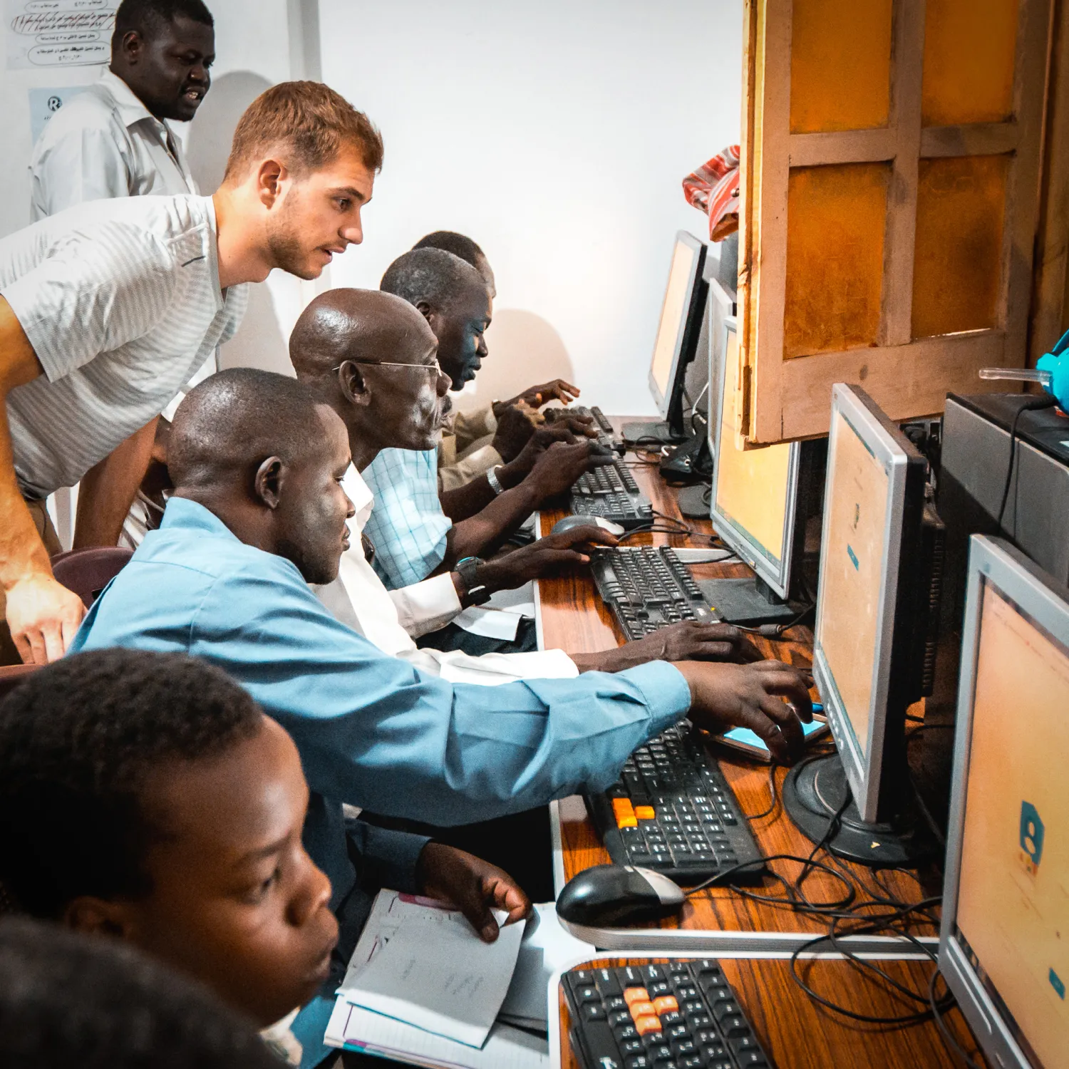 An outreach leader overlooking outreach students working at computers.