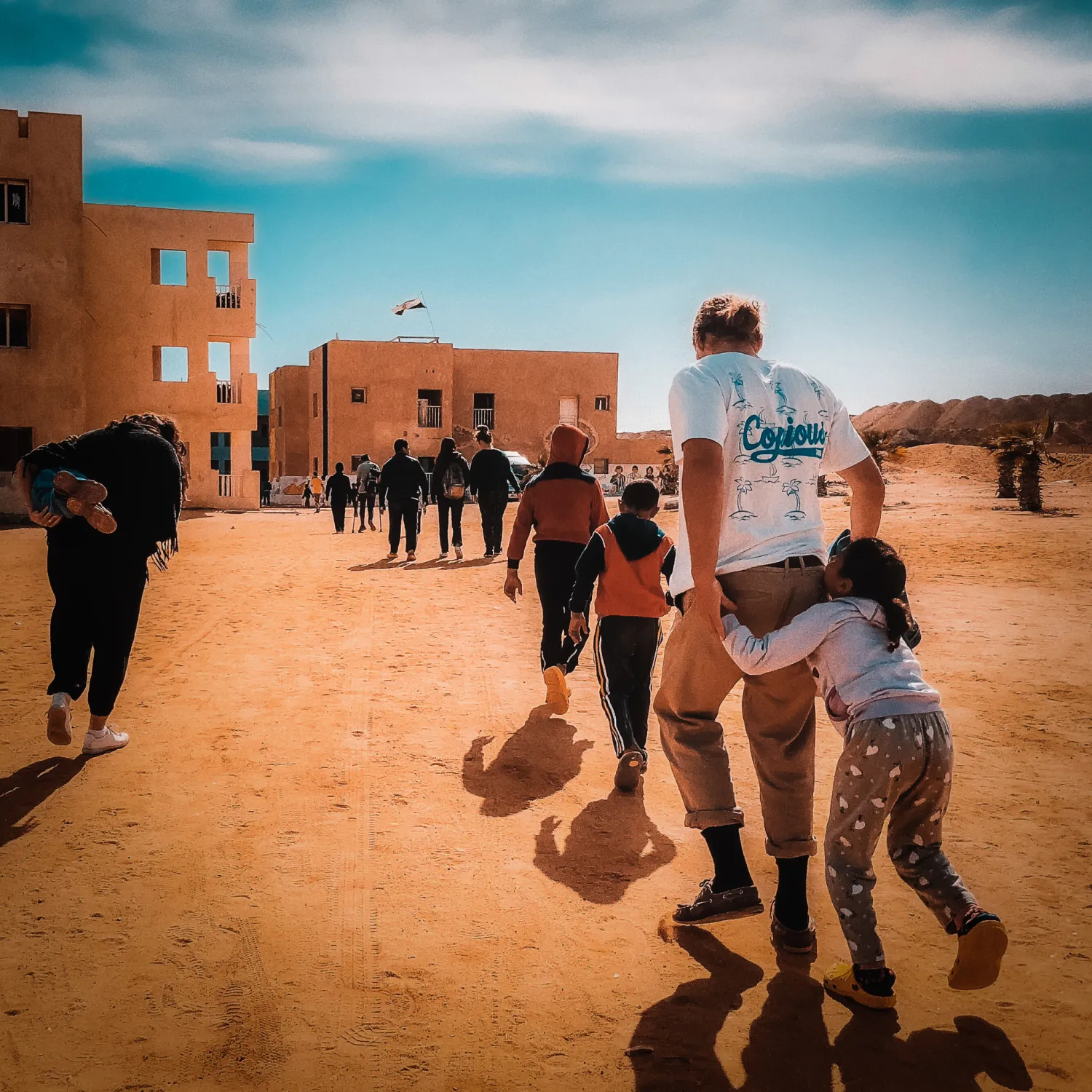 An outreach leader playing with outreach children outside in a sandy area.