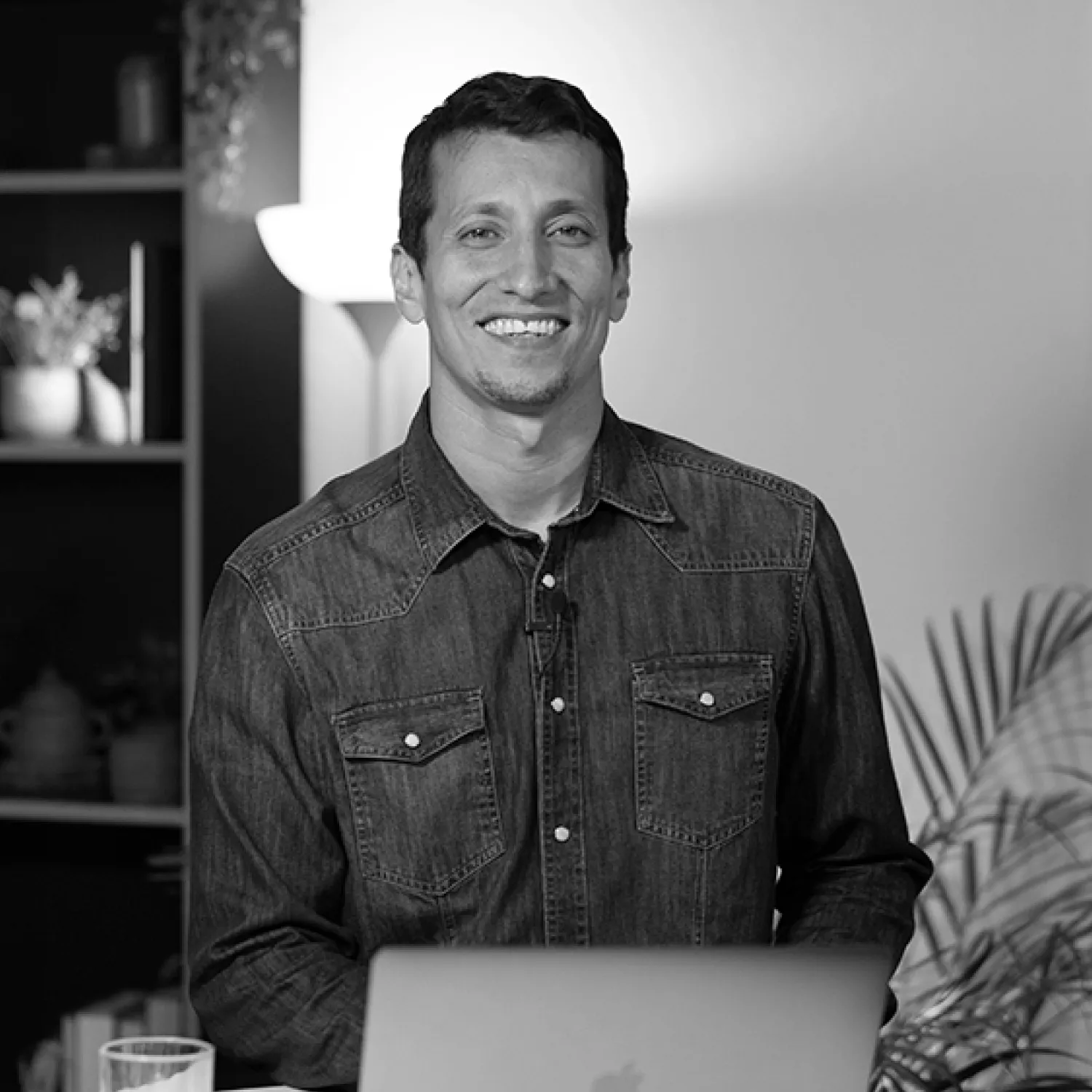 A man smiling at his desk in front of his laptop.