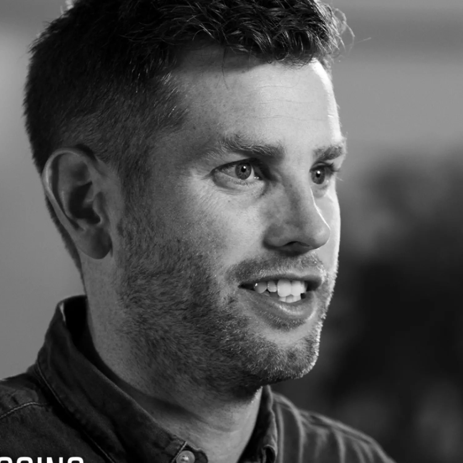 A close up side profile image of a man smiling.