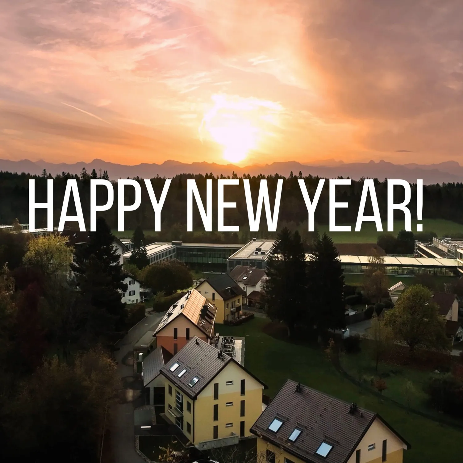 An image of the town of Lausanne with the sun rising in the background with the caption, 'Happy New Year!'