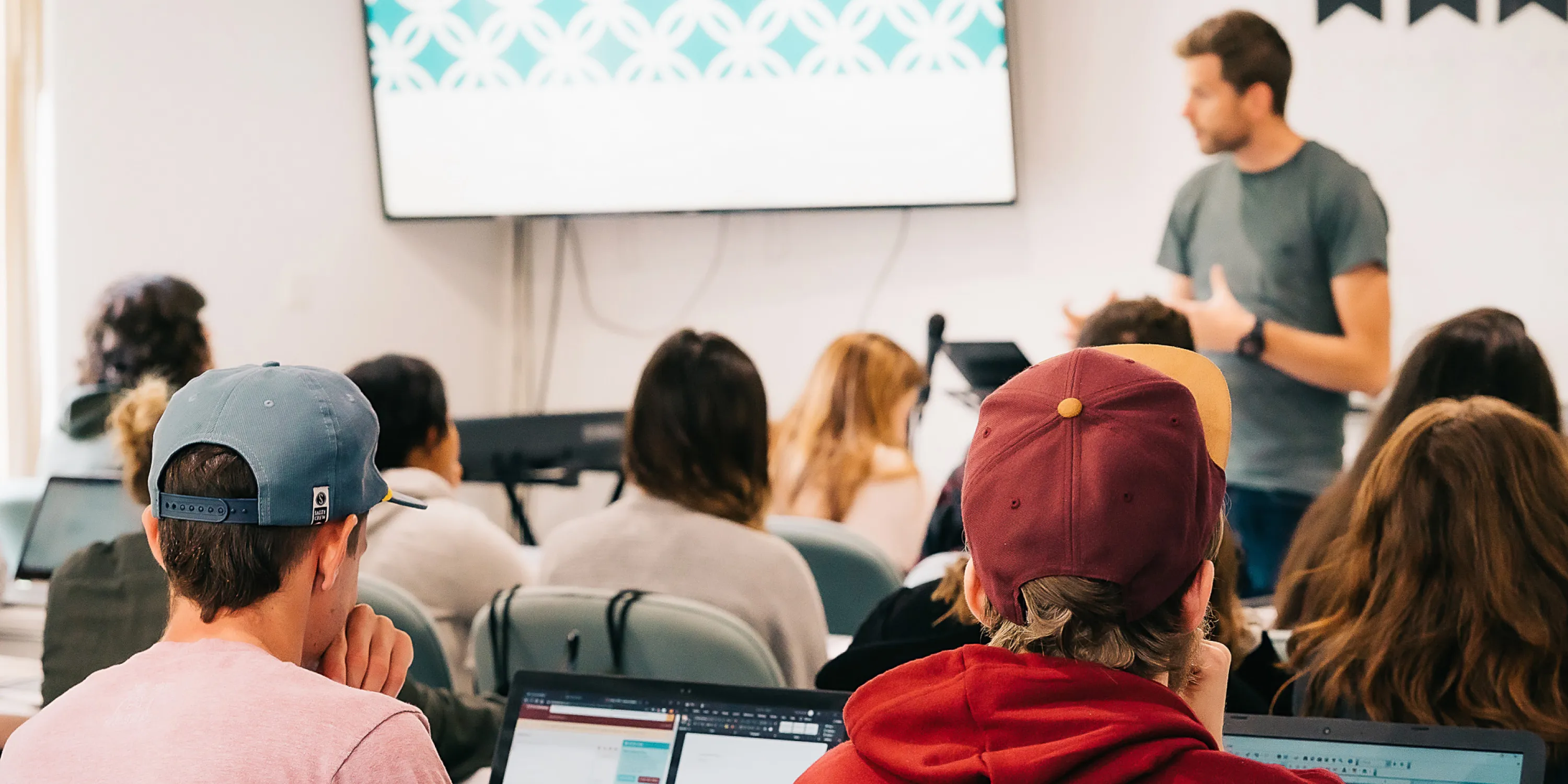 a lecturer standing in front of a group of seated students.