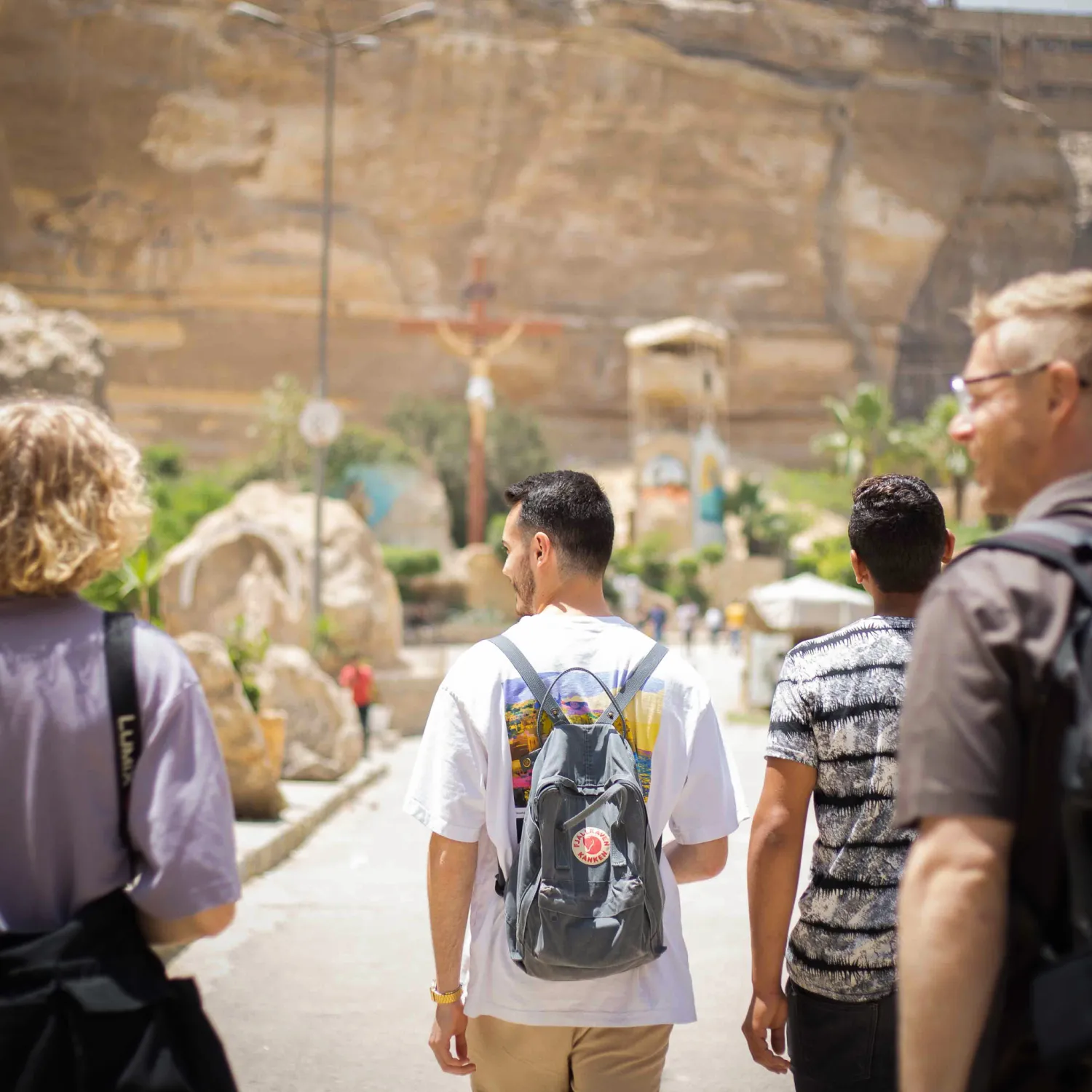 A group of students walking with bags towards a mountain.