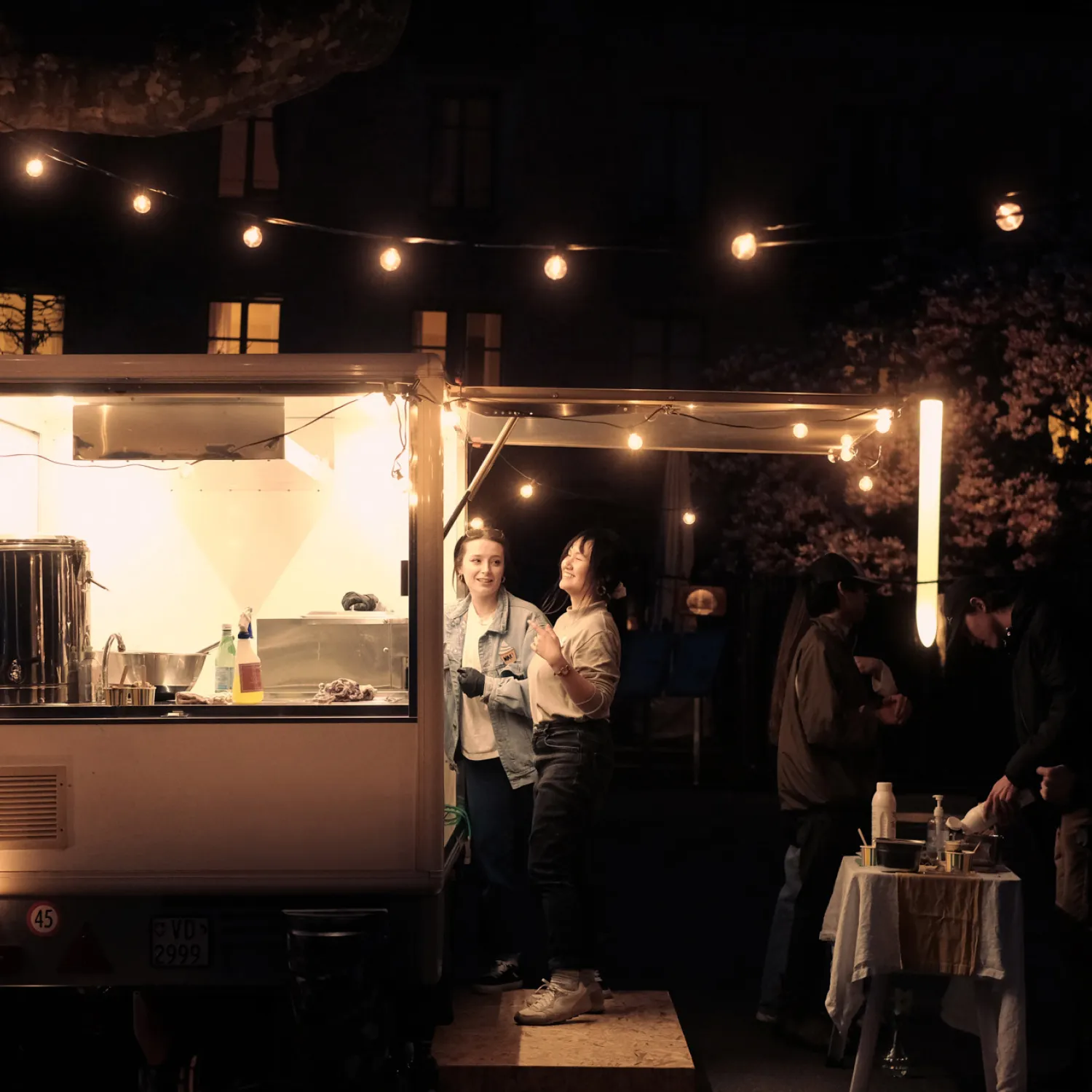 Two students at an evening food truck underneath fairy lights.