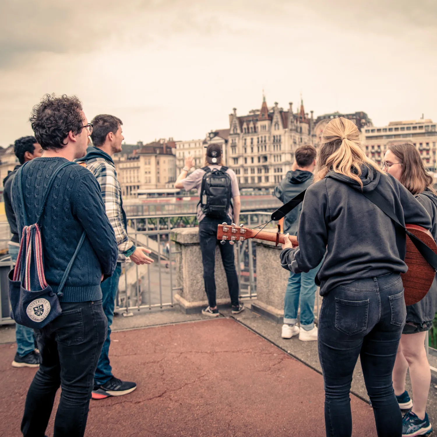 A group of students standing and singing in a town centre with buildings in the background.