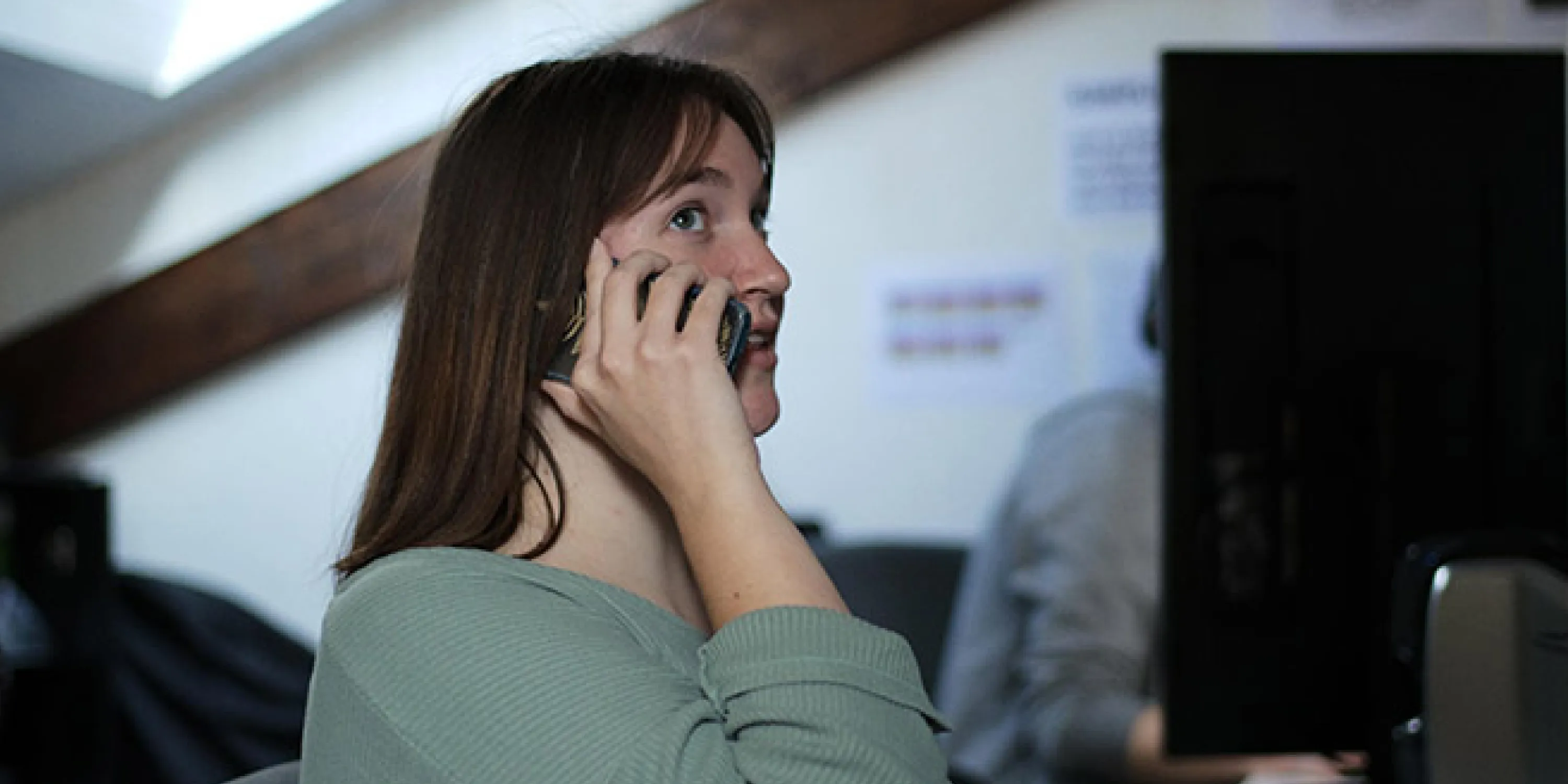 A side profile of a woman holding her phone have a conversation.