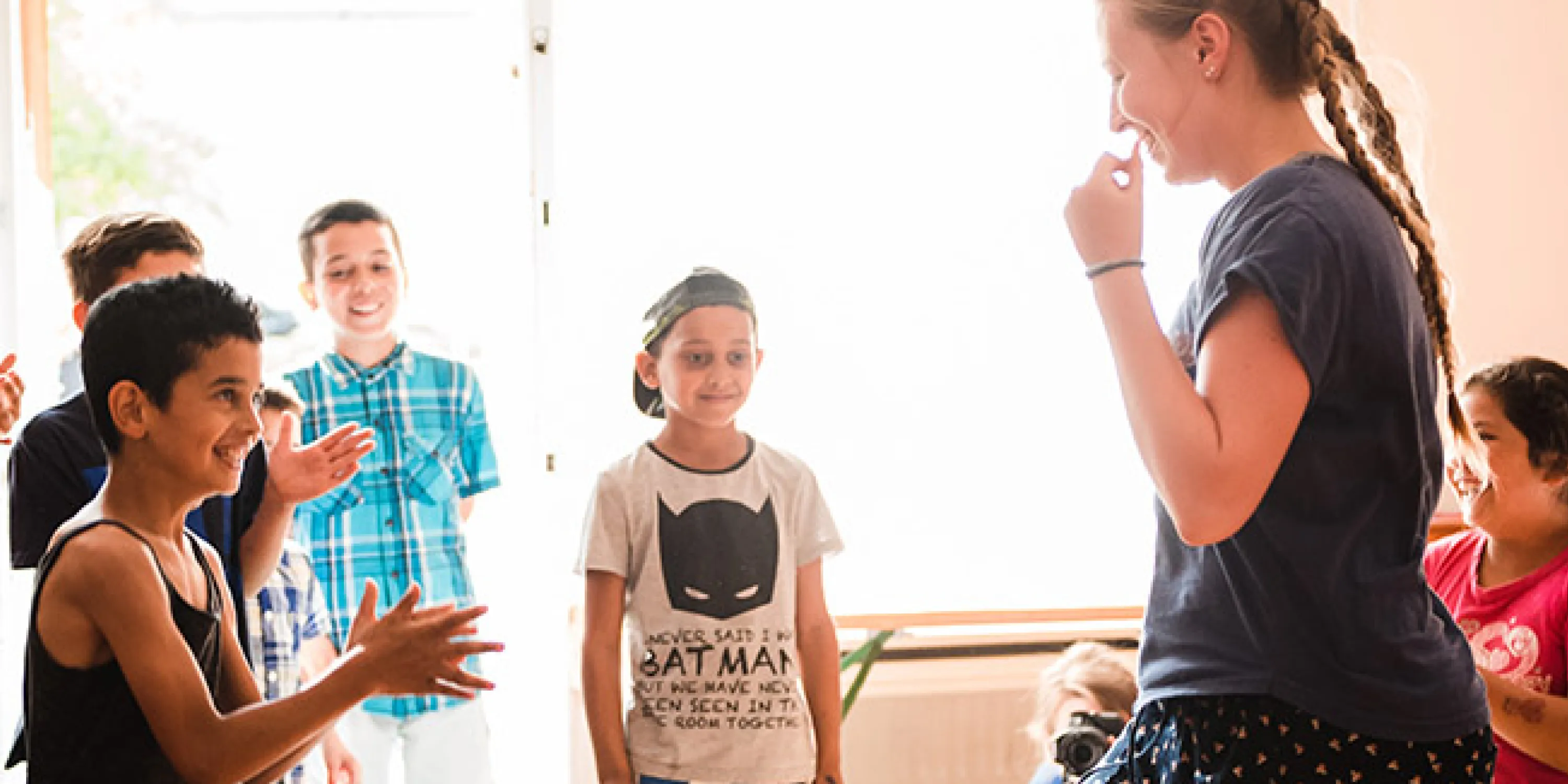 An image of an outreach student interacting with a group of outreach children.