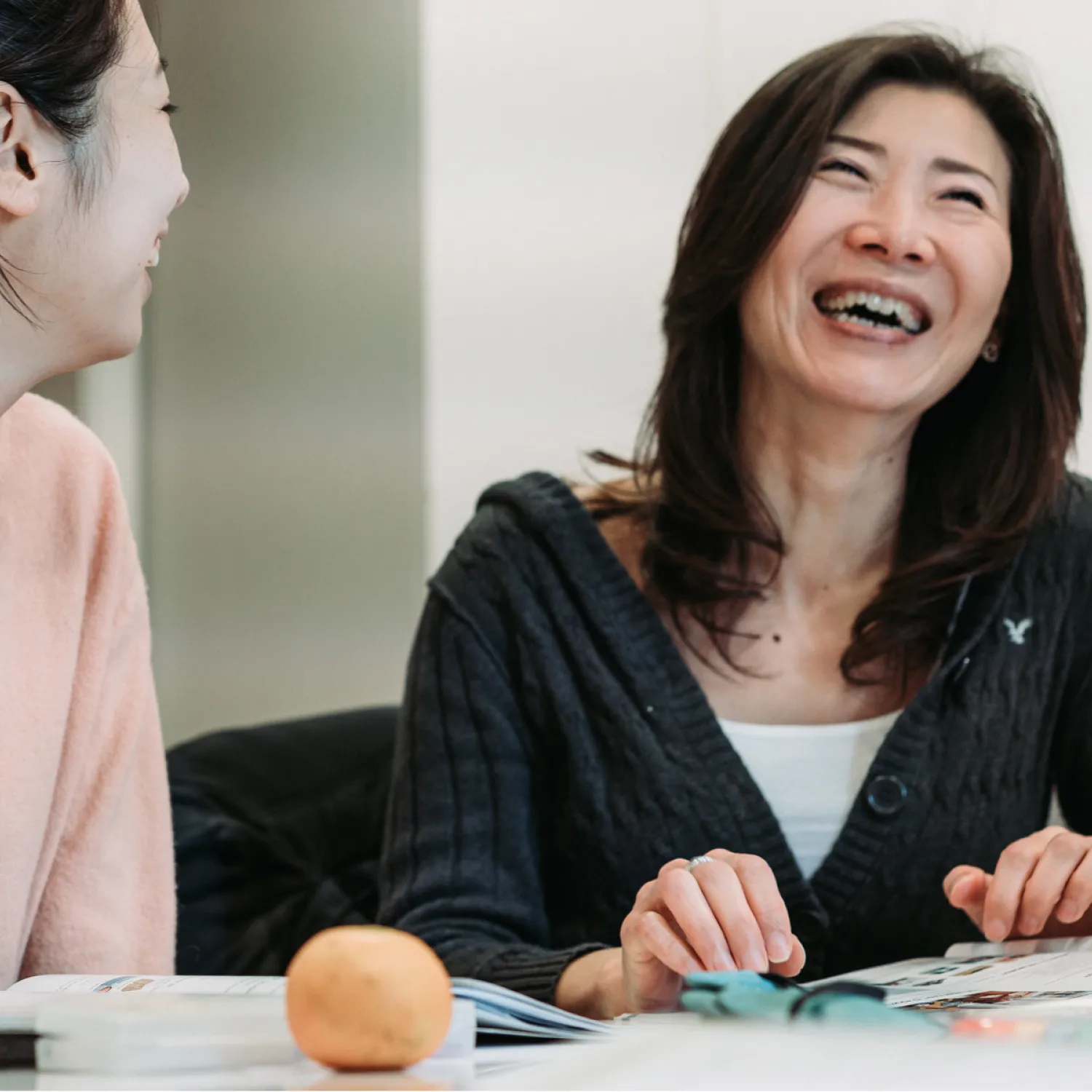 Two students laughing while seated with their notes on their desk.