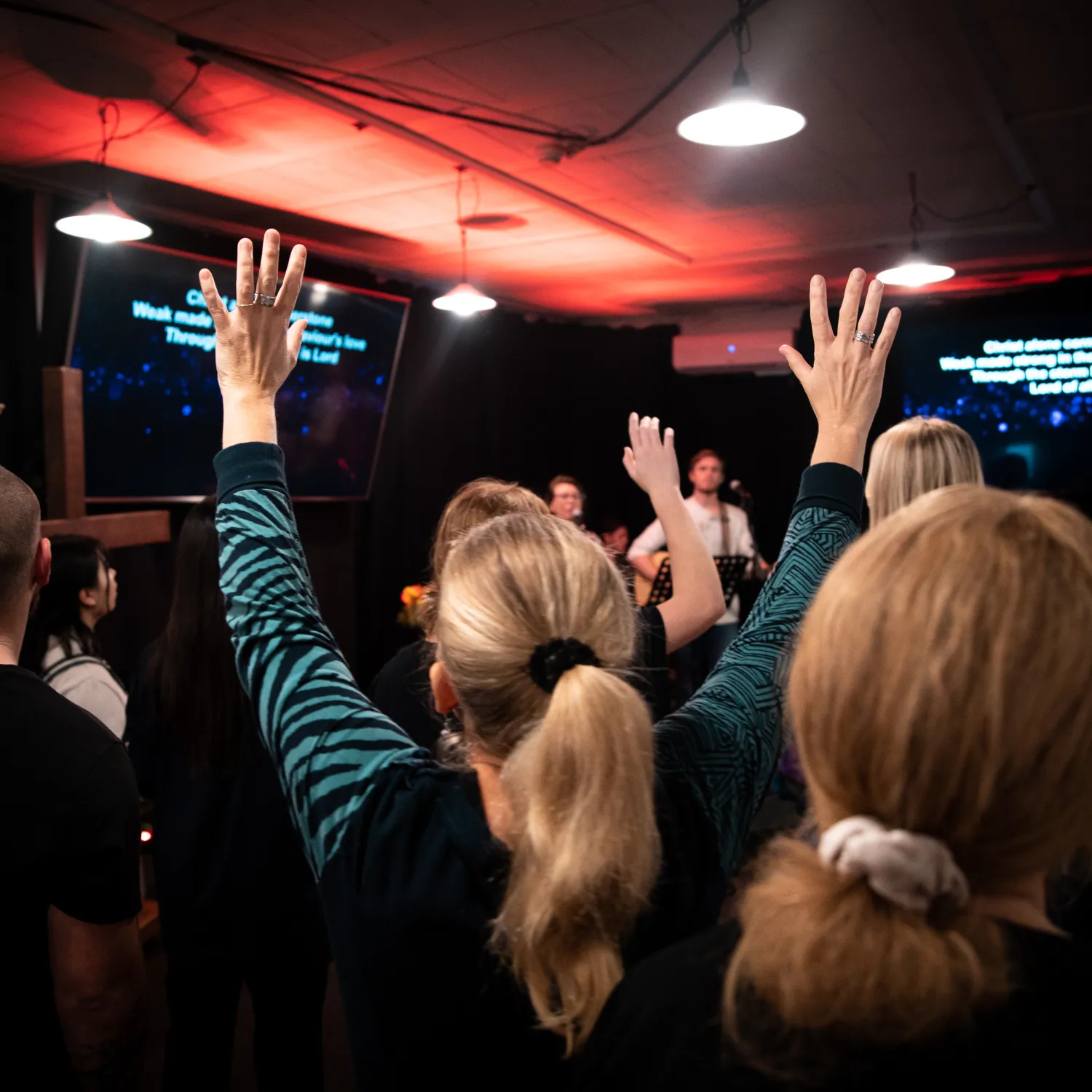A group of students with their hands up in the air during worship in DTS school at YWAM Lausanne.